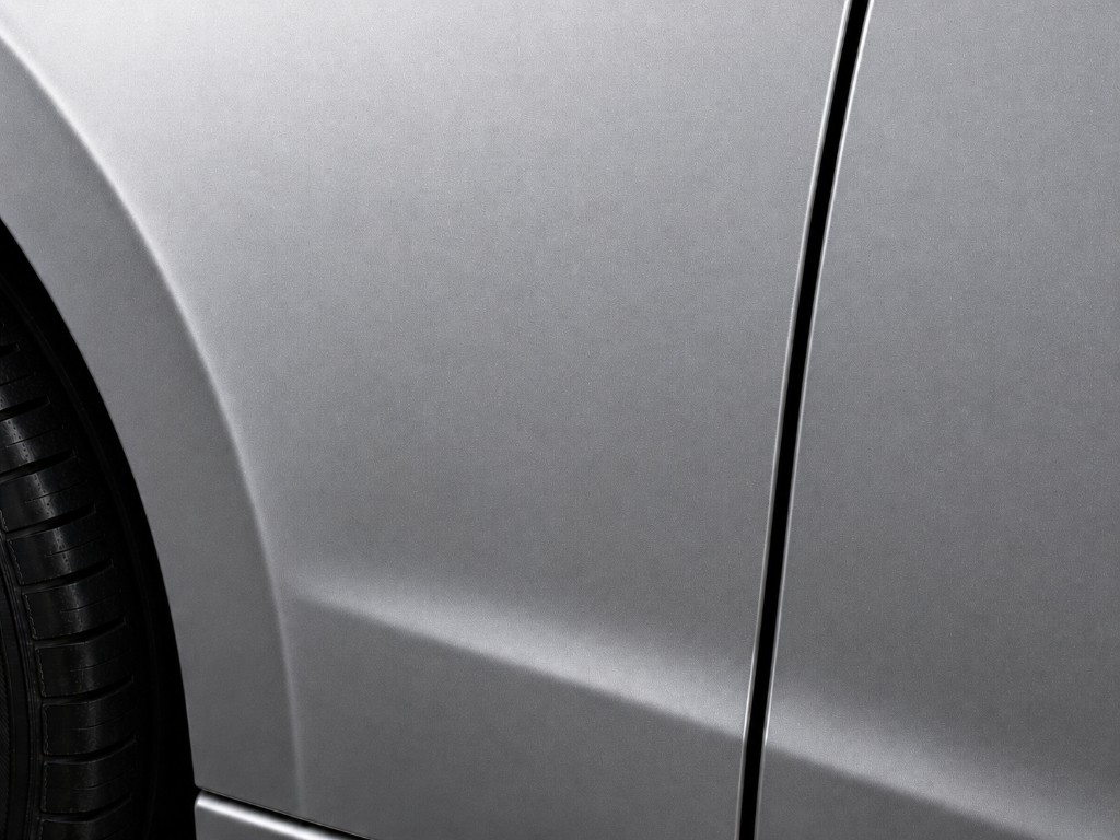 Metallic silver car body panels with a vertical door seam and part of a tire visible, showing a smooth factory-style finish.